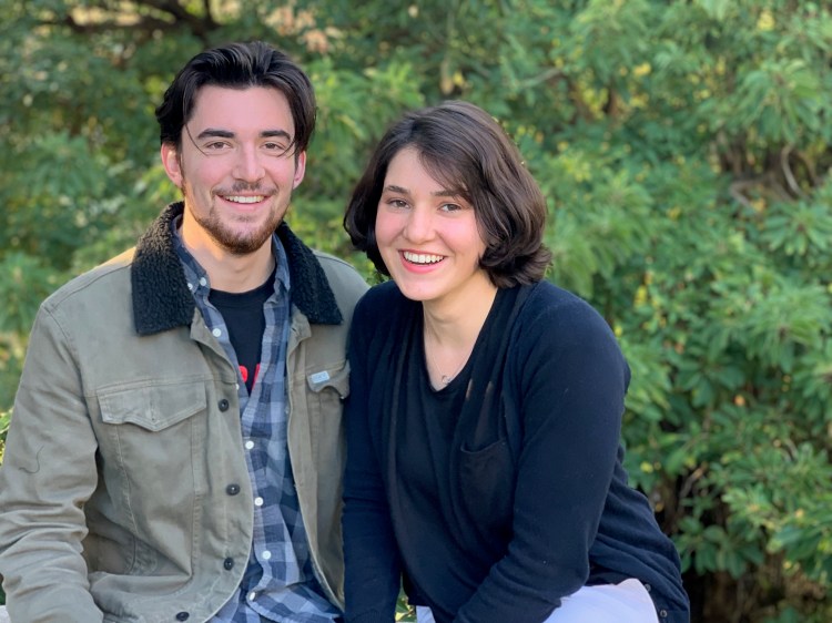Emily and Grant sitting in front of spring foliage